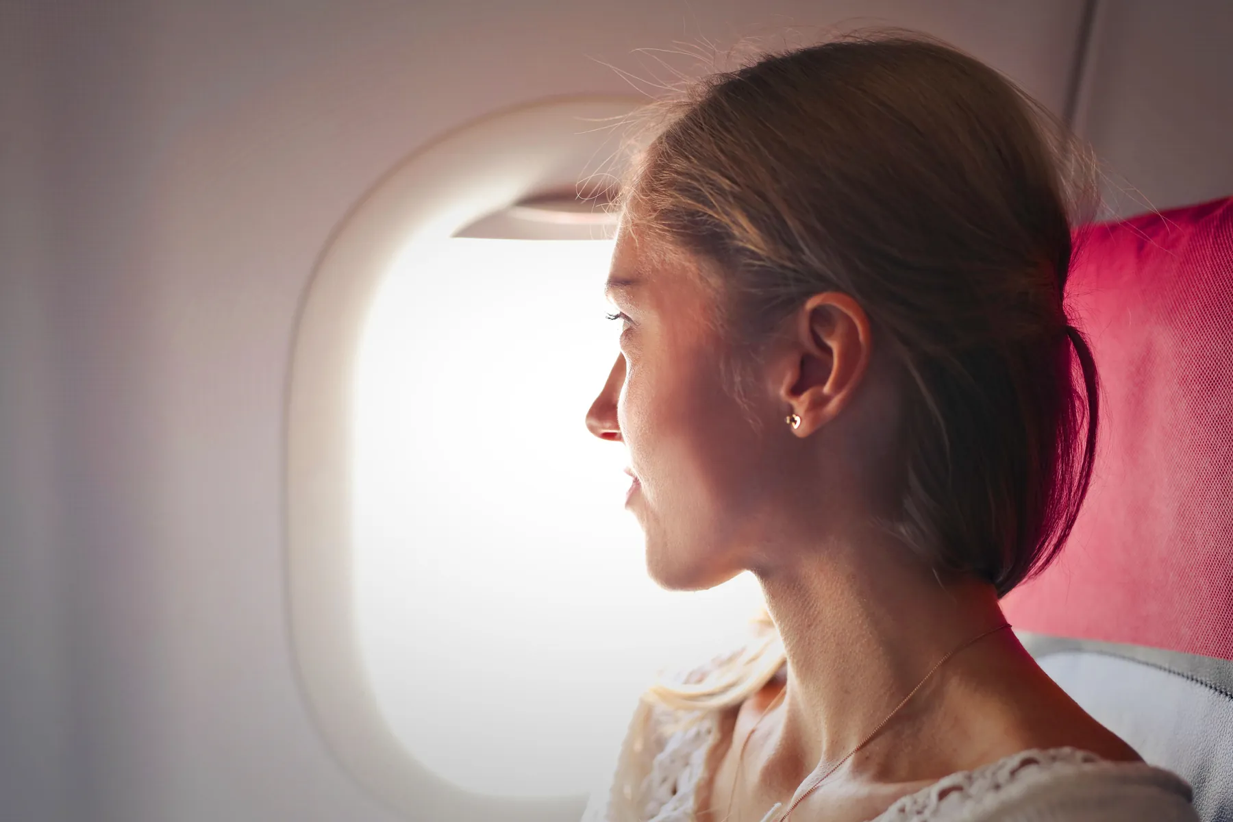 Traveller looking through an aircraft window in warm daylight